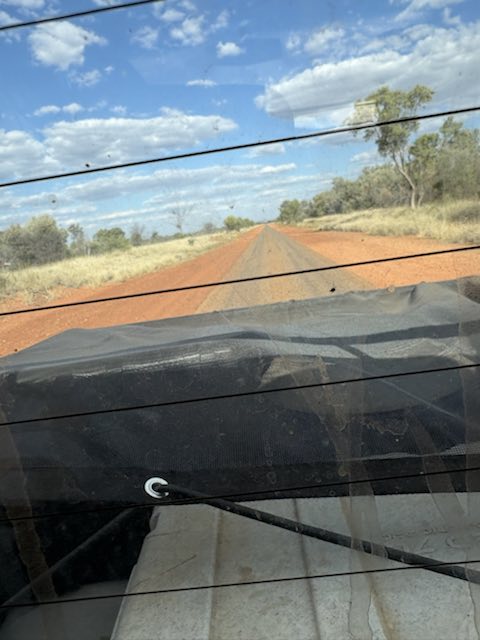 A red dirt road leading towards a remote community